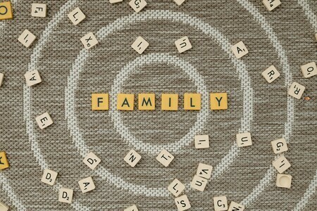 Scrabble pieces spelling out family in the center of a board with a circular pattern underneath