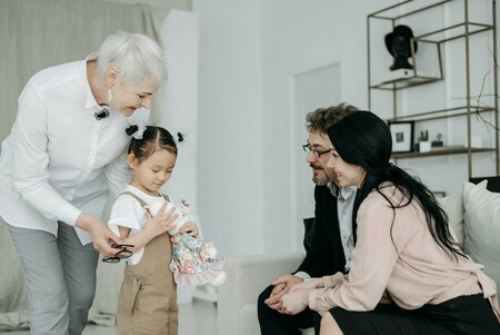 Family observing young girl with caregiver as she plays with a plush toy